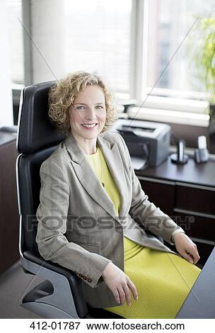 Stock Photo - Businesswoman smiling at desk. Fotosearch