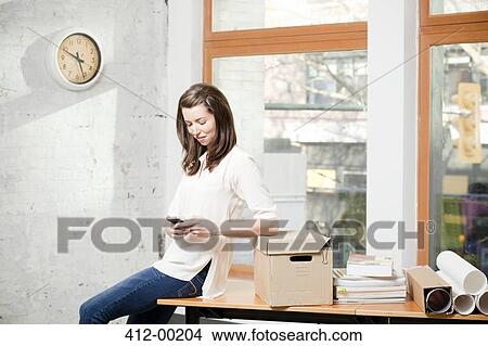 Picture - Businesswoman using cell phone in office. Fotosearch
