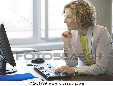 Businesswoman working at computer at desk View Large Photo Image Stock Photo - Businesswoman working at computer at desk. Fotosearch