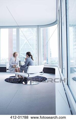 Stock Photo - Businesswomen talking in office lobby. Fotosearch
