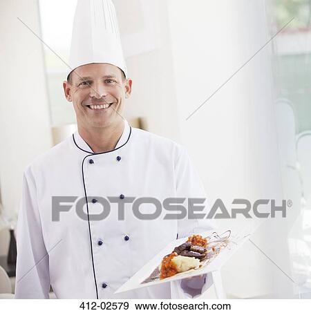 Chef carrying plate of food in restaurant View Large Photo Image Stock Photo - Chef carrying plate of food in restaurant. Fotosearch