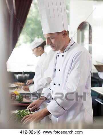 Stock Photograph - Chef chopping vegetables in restaurant kitchen. Fotosearch