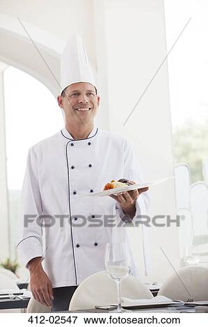 Chef holding plate of food in restaurant View Large Photo Image Stock Photo - Chef holding plate of food in restaurant. Fotosearch