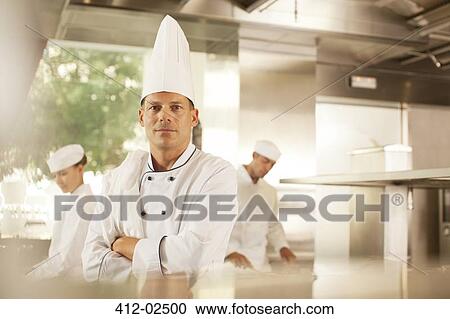Stock Image - Chef standing in restaurant kitchen. Fotosearch