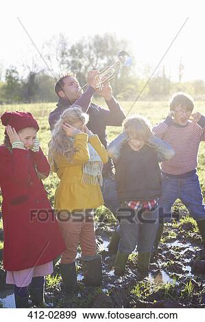 Children covering their ears as father plays trumpet View Large Photo Image Stock Photo - Children covering their ears as father plays trumpet. Fotosearch