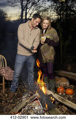 Couple relaxing by campfire at sunset View Large Photo Image Stock Image - Couple relaxing by campfire at sunset. Fotosearch