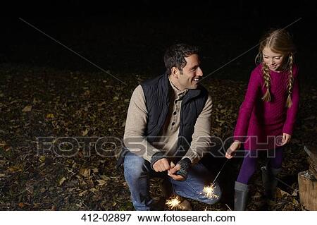Father and daughter playing with sparklers View Large Photo Image Stock Photo - Father and daughter playing with sparklers. Fotosearch