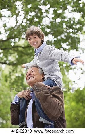 Man carrying grandson on shoulders outdoors View Large Photo Image Stock Photo - Man carrying grandson on shoulders outdoors. Fotosearch