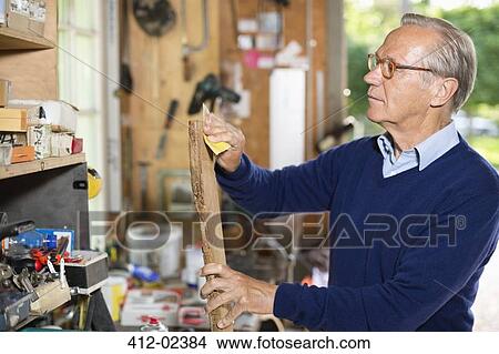 Picture - Man sanding wood in garage. Fotosearch