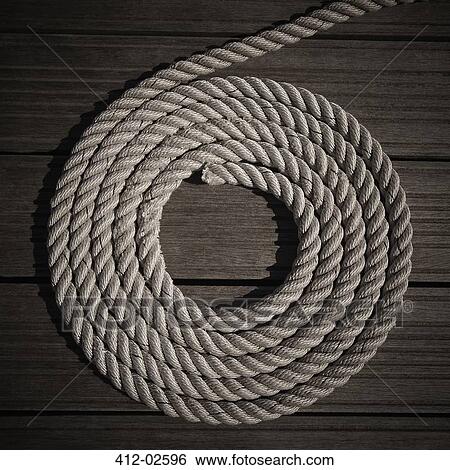 Stock Photograph - Rope coiled into circle on boardwalk. Fotosearch