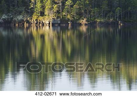 Stock Image - Rural landscape reflected in still lake. Fotosearch