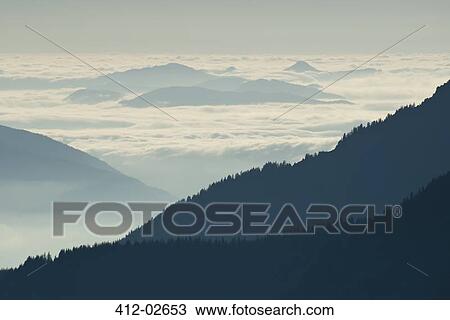 Stock Image - Silhouette of mountainside with clouds. Fotosearch