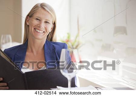 Smiling woman reading menu in restaurant View Large Photo Image Picture - Smiling woman reading menu in restaurant. Fotosearch