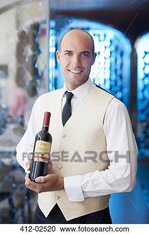 Waiter holding bottle of wine in restaurant View Large Photo Image Stock Image - Waiter holding bottle of wine in restaurant. Fotosearch