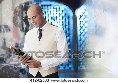 Waiter reading bottle of wine in kitchen View Large Photo Image Stock Image - Waiter reading bottle of wine in kitchen. Fotosearch