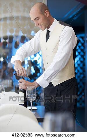 Waiter uncorking bottle of wine in restaurant View Large Photo Image Stock Image - Waiter uncorking bottle of wine in restaurant. Fotosearch