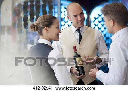Waiters discussing bottle of wine in restaurant View Large Photo Image Stock Image - Waiters discussing bottle of wine in restaurant. Fotosearch