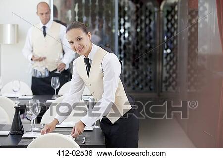Stock Photograph - Waitress setting table in restaurant. Fotosearch