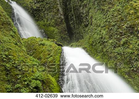 Waterfall rushing over green rocky hillside View Large Photo Image Stock Photo - Waterfall rushing over green rocky hillside. Fotosearch