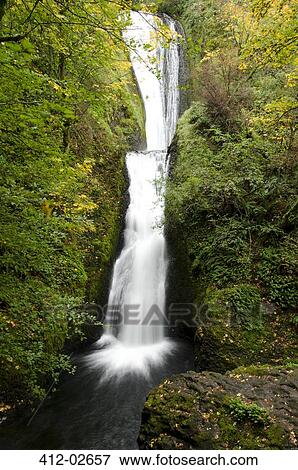 Waterfall rushing over rocky hillside View Large Photo Image Stock Photo - Waterfall rushing over rocky hillside. Fotosearch