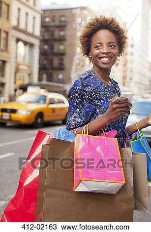 Woman carrying shopping bags on city street View Large Photo Image Stock Image - Woman carrying shopping bags on city street. Fotosearch