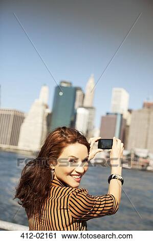 Stock Image - Woman taking picture of city cityscape. Fotosearch