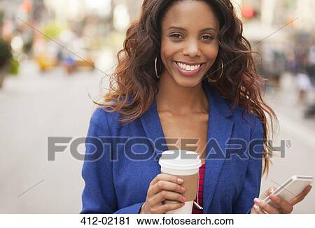 Stock Image - Woman using cell phone on city street. Fotosearch