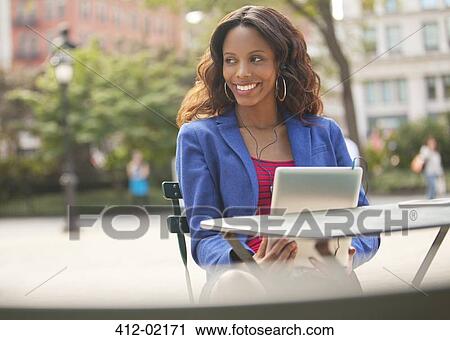 Stock Image - Woman using digital tablet at sidewalk cafe. Fotosearch