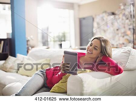 Woman using digital tablet on sofa View Large Photo Image Stock Photography - Woman using digital tablet on sofa. Fotosearch