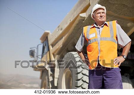 Worker standing by machinery on site View Large Photo Image Stock Photograph - Worker standing by machinery on site. Fotosearch