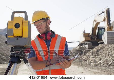 Picture - Worker using leveling equipment in quarry. Fotosearch