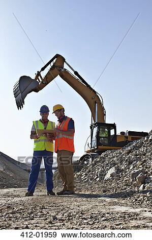 Workers talking by digger in quarry View Large Photo Image Stock Photo - Workers talking by digger in quarry. Fotosearch