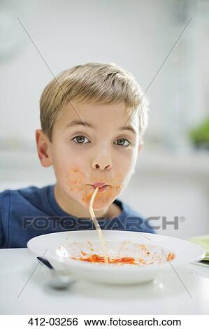 Stock Photograph - Boy slurping spaghetti at table. Fotosearch