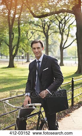 Businessman sitting on bicycle in urban park View Large Photo Image Stock Image - Businessman sitting on bicycle in urban park. Fotosearch