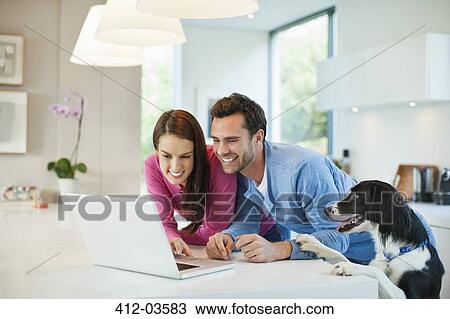 Couple using laptop with dog at table View Large Photo Image Stock Image - Couple using laptop with dog at table. Fotosearch