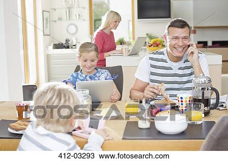 Family using technology at breakfast View Large Photo Image Stock Image - Family using technology at breakfast. Fotosearch