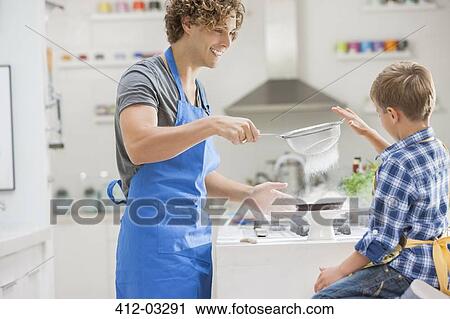 Stock Image - Father and son baking in kitchen. Fotosearch