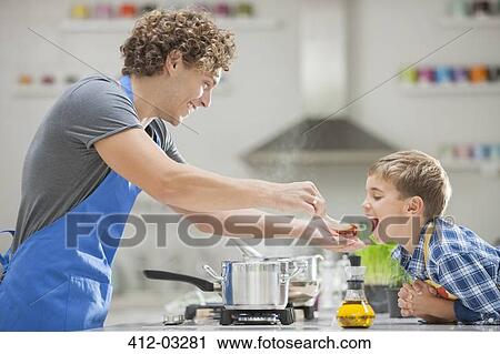 Stock Image - Father and son cooking in kitchen. Fotosearch