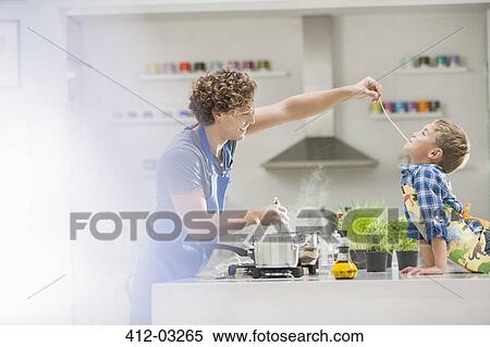 Stock Photography - Father and son cooking in kitchen. Fotosearch