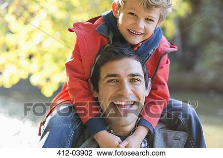 Father carrying son on shoulders in park View Large Photo Image Stock Image - Father carrying son on shoulders in park. Fotosearch