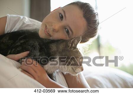 Girl petting cat on bed View Large Photo Image Stock Photo - Girl petting cat on bed. Fotosearch