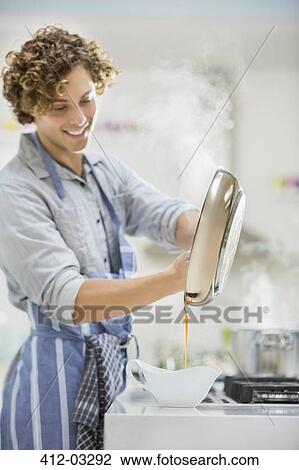 Stock Image - Man cooking in kitchen. Fotosearch