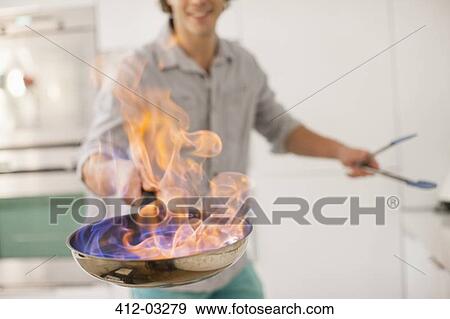 Man cooking with fire in kitchen View Large Photo Image Stock Photo - Man cooking with fire in kitchen. Fotosearch