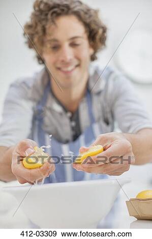 Stock Photo - Man squeezing lemons in kitchen. Fotosearch