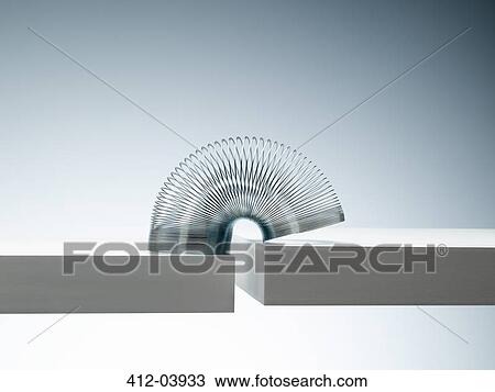 Metal slinky spanning space between blocks View Large Photo Image Stock Image - Metal slinky spanning space between blocks. Fotosearch