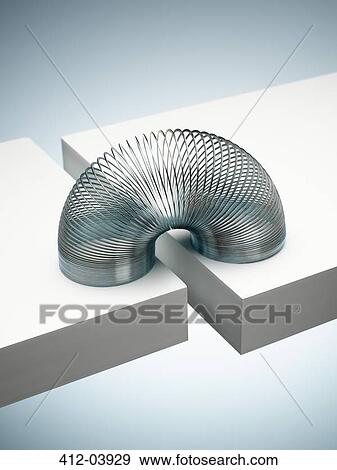 Metal slinky spanning space between blocks View Large Photo Image Stock Photo - Metal slinky spanning space between blocks. Fotosearch