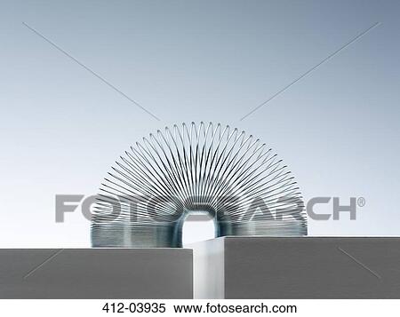Metal slinky spanning space between blocks View Large Photo Image Stock Photography - Metal slinky spanning space between blocks. Fotosearch