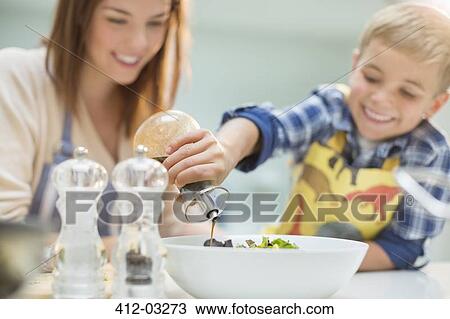 Stock Image - Mother and son making salad in kitchen. Fotosearch