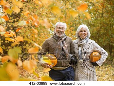 Older couple carrying pumpkins in park View Large Photo Image Stock Photo - Older couple carrying pumpkins in park. Fotosearch