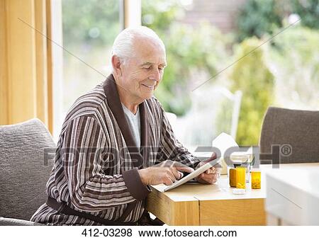 Stock Photo - Older man using tablet computer at table. Fotosearch